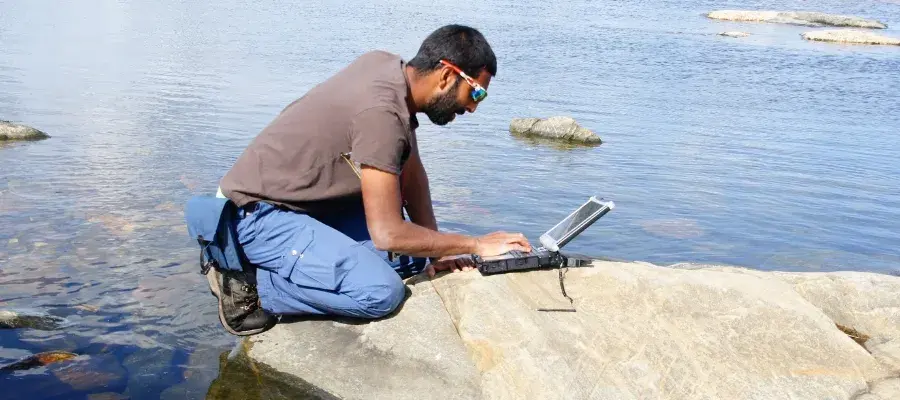 Romesh conducting survey work on his laptop.